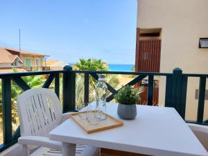 una mesa blanca y sillas en un balcón con vistas al océano en Branco Sea Holiday Apartments, en Santa Maria