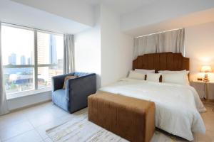 sypialnia z dużym łóżkiem i niebieskim krzesłem w obiekcie Sunny Seaside 2 Bedroom Apartment, Dubai Marina w Dubaju