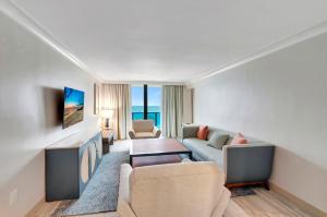 Tideline Palm Beach Ocean Resort and Spa في بالم بيتش: غرفة معيشة مع أريكة وطاولة