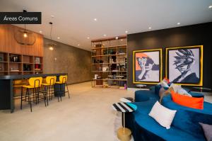 a living room with a blue couch and a bar at Charlie For You Moema in Sao Paulo