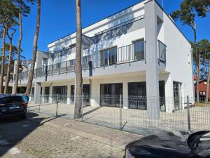 ein weißes Gebäude mit einem Zaun davor in der Unterkunft Apartamenty Fala in Międzywodzie