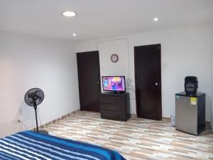 1 dormitorio con cama y vestidor con TV en Casa de renta vacacional Andy-Cali -Valle del Cauca en Cali