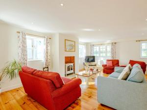 a living room with two red chairs and a couch at 4 bed in Lulworth CHRIC in West Lulworth