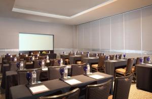 a conference room with tables and chairs and a screen at PO Hotel Semarang in Semarang