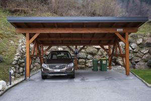 a carport with a car parked under a roof at MY TIME Holiday House with sauna in Zgornje Gorje