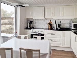 una cocina con armarios blancos y una mesa y sillas blancas. en Holiday home SKÖVDE en Skövde
