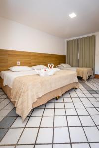 two beds in a hotel room with towels on them at Arraial do Sol Beach Hotel in Arraial d'Ajuda +89 photos