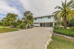 Una casa con palmeras y un camino de grava. en Down Time, en Sanibel