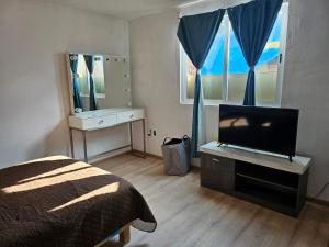 um quarto com uma cama e uma televisão de ecrã plano em Hospedaje Mamá Coti em Santa Ana Chiautempan