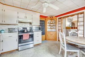 a kitchen with white cabinets and a table and a dining room at Quiet Port Royal Home with Deck, Near Juniata River! in Mifflintown