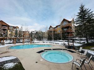 a swimming pool in a yard with snow on the ground at Canmore Mountain Retreat - Heated Pool & Hot-tub in Canmore