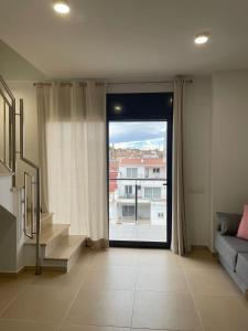 a living room with a large window and a staircase at Luminoso dúplex con parking in Terrassa