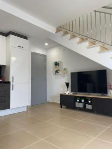 a living room with a staircase and a television at Luminoso dúplex con parking in Terrassa