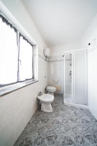 a white bathroom with a toilet and a shower at Bosa Mare & Relax in Bosa Marina