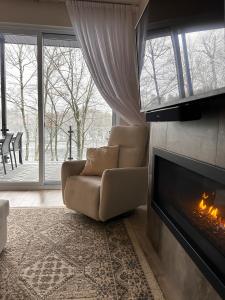 a living room with a chair and a fireplace at Le Riverain - Condo neuf au bord de l'eau in Shawinigan