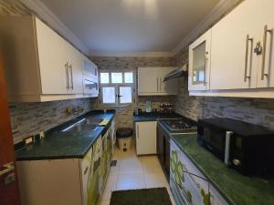 a kitchen with white cabinets and green counter tops at YOUVALA Serviced Apartments City Star in 6th Of October