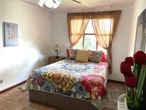 una camera con letto e finestra con fiori rossi di Quizur, Culturita de Paz a Piedades