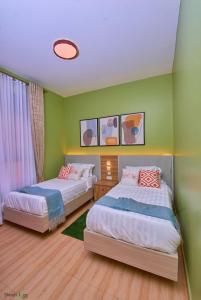 two beds in a room with green walls at Shosholoza Homes in Wakiso