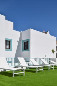 a row of white benches in front of a building at A Muralha in Tavira