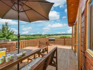 a wooden deck with a wooden bench and an umbrella at 3 Bed in Lenham 86252 in Lenham