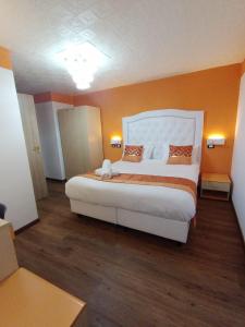 a bedroom with a large white bed with orange walls at Hotel Veronese in Genova