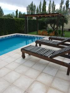 una piscina con un banco de madera junto a una piscina en Cabañas La Soñada en San Rafael