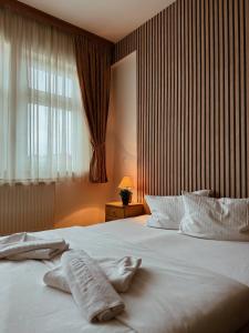 een slaapkamer met een groot wit bed en 2 handdoeken bij Hotel Kupres in Kupres