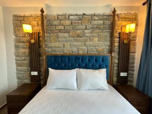 a bed with a blue headboard and a brick wall at İLİA BUTİK OTEL in Eceabat