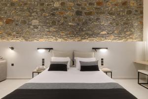 een slaapkamer met een groot bed en een stenen muur bij Zaira Hotel in Skála Loutrón