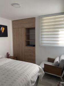 a bedroom with a bed and a chair and a window at Apto Santa Marta in Santa Marta +3 photos