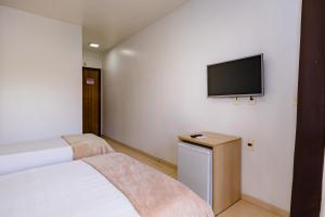a bedroom with a bed and a tv on the wall at Casa Blanca Park Hotel in Porto Seguro