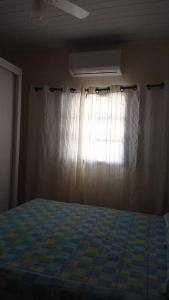 een slaapkamer met een bed met een gordijn en een raam bij casa privativa para família com ar condicionado in Olímpia