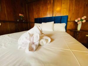 een bed met witte handdoeken en een blauw hoofdeinde bij Wooden House Mindo - Casa de Las Nevadas in Mindo