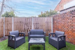 a backyard with three chairs and a table and a fence at Stylish Retreat in Nuneaton Centre with Sofa Bed, Garden and Super Fast Wi-Fi in Nuneaton