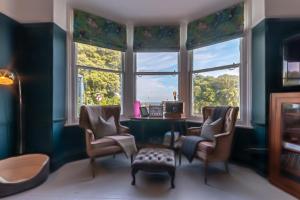 a room with a desk and chairs and windows at Victorian Apartment With Sea Views By Adliv Host in Ramsgate