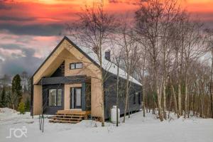 a small house in the snow with a sunset at Villa Scandinave 3 CAC avec 3 SDB privées & SPA in Pont-Rouge