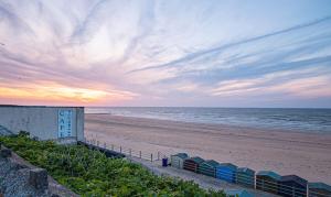 a beach with umbrellas and the ocean at sunset at Beautiful Margate Coastal Home With Parking in Margate