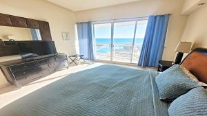 een slaapkamer met een bed en een groot raam met uitzicht op de oceaan bij Encanto Living 304 Spacious, 2 Bedroom Ocean View!! in Playa Encanto