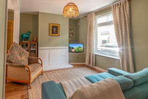 un soggiorno con divano blu e TV di 3-bed Hidden Gem Of A Cottage In Margate a Margate