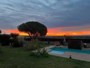 een zwembad in een tuin met een zonsondergang op de achtergrond bij Villa Sol Peralada Golf in Peralada