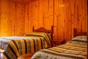 2 camas en una habitación con paredes de madera en Pousada Vale Verde, en Campos do Jordão