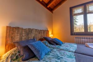 Un dormitorio con una cama con almohadas azules y una ventana en Arpetxea casa rural, en Roncal