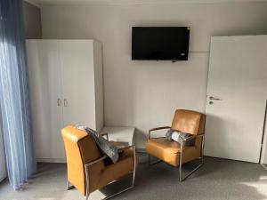 una camera con due sedie e una TV a parete di Pension Gauerbach Lingen a Lingen