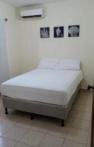 Una cama blanca en una habitación con en Casa en la playa puerto cortes, en Puerto Cortés