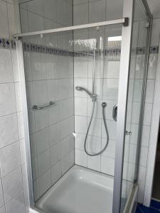 een douche met een glazen deur in de badkamer bij Pension Gauerbach Lingen in Lingen