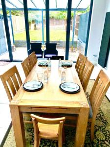 a wooden table with chairs and plates and glasses on it at Luxury 5 bedroom house with Private car park in London in Hendon