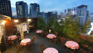 a rooftop patio with tables and chairs and a city skyline at Hotel Skypark Myeongdong 1 in Seoul