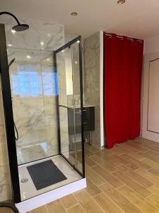 a glass shower in a room with a red curtain at Carol California in Chevigny-Saint-Sauveur