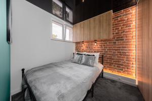 uma cama num quarto com uma parede de tijolos em Apartament Atlas Arena em Lódź