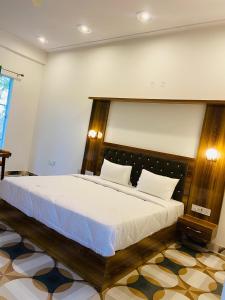 a bedroom with a large bed with a wooden headboard at New Corbett Hotel and Resort in Belparāo